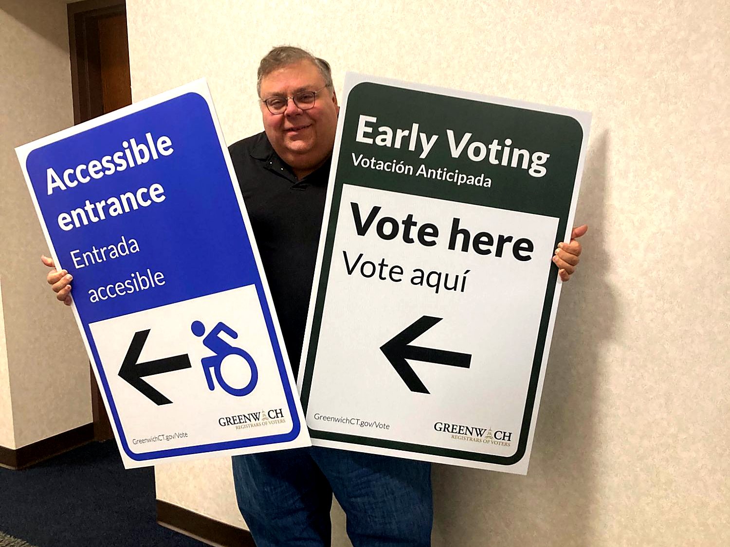 Fred DeCaro holding bilingual early voting signs